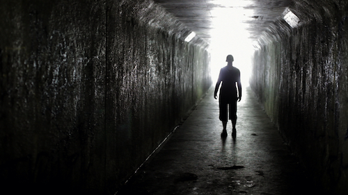 A character standing inside a tunnel, backlit